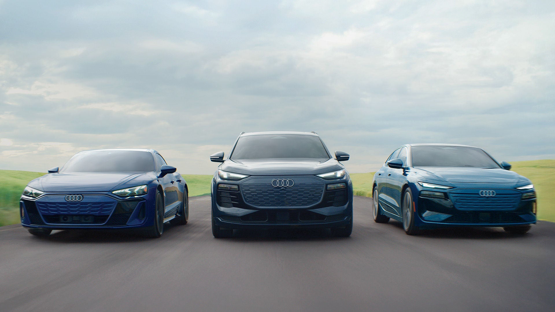 Three Audi EVs in a lineup, accelerating.